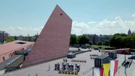 Gdansk-Museum-of-Second-World-War-over-the-cloudy-sky---Aerial-pull-back-motion-revealing-polish-national-Flags-on-flagpoles