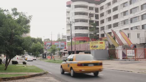 Der-Blick-Auf-Ein-Verlassenes-Hotel-Und-Eine-Wohngebäudestruktur-Neben-Einer-Autowaschanlage-Führt-Zu-Einem-Taxi,-Das-Die-Straße-Samuel-Lewis-Im-Bella-Vista-Von-Panama-Stadt-Entlangfährt