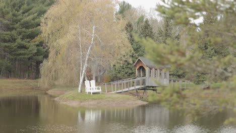 Hermoso-Estanque-Con-Una-Isla-Situada-En-El-Medio-Con-Un-Puente-De-Madera-Que-Se-Extiende-Hasta-él-En-El-Rancho-Bean-Town-Cerca-De-Ottawa