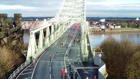 Charity-Santa-dash-fun-run-over-Runcorn-Silver-Jubilee-bridge-Aerial-view-short-tilt-up