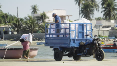 Hombres-En-El-Trabajo-Descargando-Materiales-De-Una-Moto-A-Un-Pequeño-Bote-Redondo