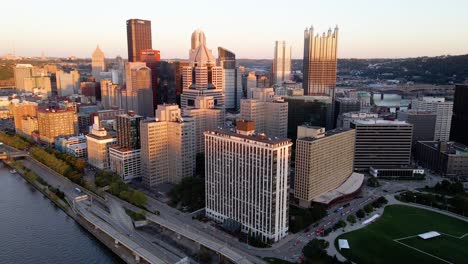 Aerial-view-deep-sunset-shadows-covering-parts-of-the-Pittsburgh-downtown---rising,-drone-shot