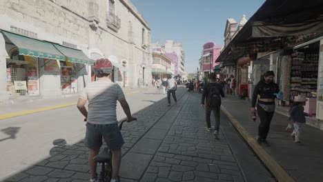 Kid-riding-a-bicycle-and-people-walking-over-the-streets-of-Oaxaca-Mexico