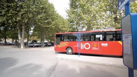 Red-Bus-Regional-Occitanie-Transport-Lio-waiting-parked-at-stop,-Pan-right-shot