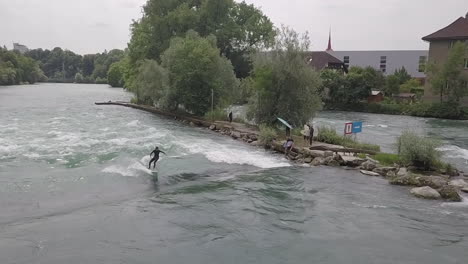 Surfista-En-Traje-De-Neopreno-Monta-Olas-Estacionarias-En-Bremgarten,-Suiza