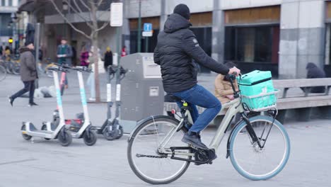 Rider-De-Deliveroo-Buscando-En-Una-Tienda-Oscura-Para-Recoger-Un-Pedido-De-Comida-Para-Una-Entrega-Rápida---Bruselas,-Bélgica