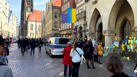 Grupo-De-Manifestantes-Que-Se-Manifiestan-Contra-La-Guerra-De-Ucrania-Contra-Rusia-Y-Putin---Hermosa-Ciudad-Alemana-Antigua-Durante-El-Día-Soleado---Ucrania-Y-Bandera-Europea---Tiro-Panorámico