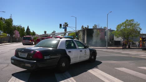 Coche-De-Policía-Y-Bomberos-En-Un-Escenario-De-Incendio-En-Un-Edificio-En-El-Soleado-Los-Ángeles,-EE.UU.