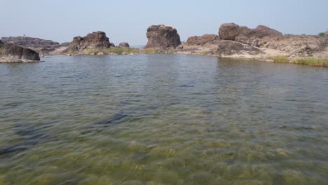 Beautiful-top-view-of-Narmada-river-in-Gujrat,-India-surrounded-by-high-rocks-in-the-hilly-terrain-in-the-background-on-a-bright-sunny-day