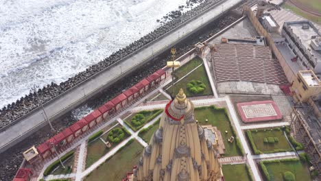 Aerial-drone-rotating-shot-of-Somnath-mandir-with-cityscape-and-sea-in-the-background