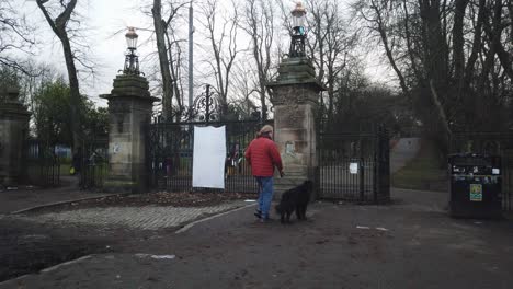 Ein-Mann-Mit-Seinem-Hund-Liest-Eine-Scheinpartyeinladung-In-Die-Downing-Street-In-Glasgow