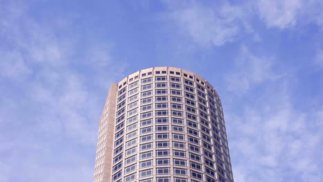 Clouds-passing-behind-contemporary-cylindrical-corporate-office-skyscraper-building