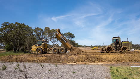 Lapso-De-Tiempo-De-Rodillos-De-Carretera-Y-Un-Camión-Volquete-Construyendo-La-Base-Del-Suelo-De-Una-Nueva-Carretera-De-Desarrollo-De-Viviendas