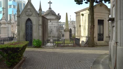 Old-Tombstones-in-Cemetery-of-Agramonte-with-Business-Buildings-in-Background