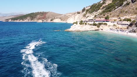 Schneller-Jetski-Segelt-über-Das-Blaue-Meer-Am-Strand-Von-Pulebardha,-Ksamil,-Albanien---Lufttransportwagen