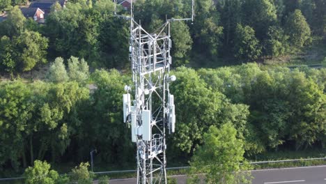 Antena-De-Torre-De-Transmisión-5g-En-El-Campo-Británico-Con-Vehículos-Que-Viajan-Entre-La-órbita-Aérea-De-Fondo-Del-Bosque-Izquierda