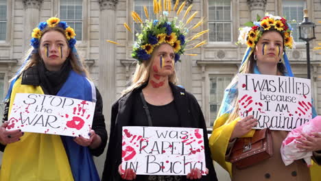 In-Zeitlupe-Halten-Blutbespritzte-Frauen-Mit-Traditionellem-Kopfschmuck-Verschiedene-Plakate-Hoch,-Um-Gegen-Russische-Kriegsverbrechen-In-Der-Ukraine-Zu-Protestieren