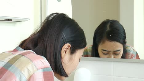 Yogyakarta,-Indonesia---June-30,-2022-:-Asian-woman-wash-her-face-in-front-of-mirror