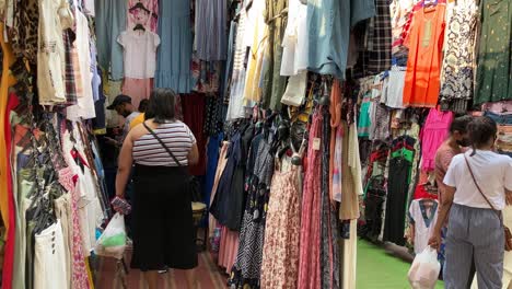 Un-Tendero-Muestra-Ropa-A-Los-Compradores-En-Un-Mercado-De-Ropa-Local