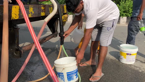 A-taxi-driver-fills-water-bottles-from-a-Government-water-tanker