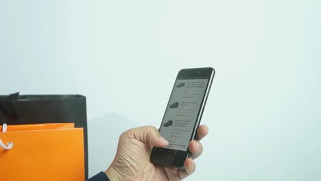 Close-up-of-a-man-shopping-for-shoes-on-his-cell-phone