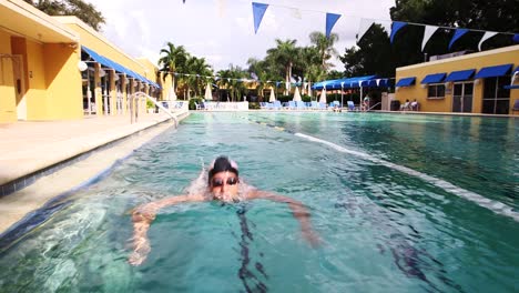 Swimmer-with-swim-cap-does-laps-in-olympic-pool,-swims-towards-camera