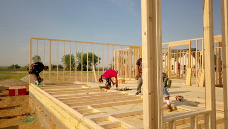 A-drone-shot-floating-around-the-construction-framers-putting-up-walls-on-a-new-home-in-the-process-of-being-built