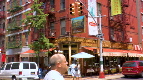 Street-scene-in-Little-Italy,-Manhattan,-people-walking-and-crossing-roads-with-traffic