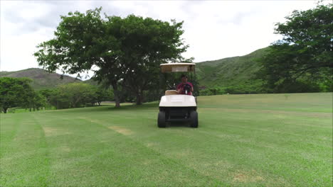 Luftaufnahme:-Luftaufnahme-Eines-Mannes,-Der-Einen-Golfwagen-Auf-Einem-Grünen-Golfplatz-Fährt