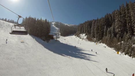 View-over-a-ski-slope-full-of-people-skiing-and-a-snowmobile-in-the-distrance-crossing-the-slope