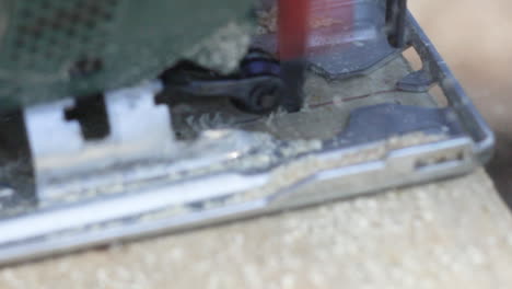 Extreme-Close-Up-of-Electrical-Jigsaw-Sawing-Through-the-Wooden-Plank-With-Sawdust-Splashing-Around