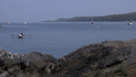 Kinder-Rudern-Sanft-Ein-Kleines-Boot-Vor-Der-Küste-Von-Durgan-Beach,-Cornwall