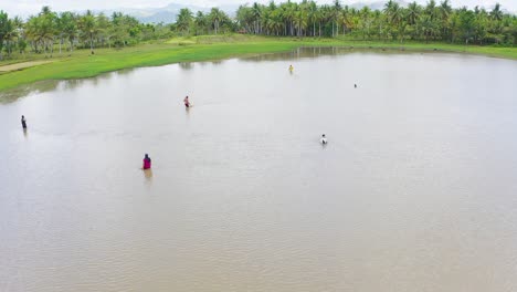 Aerial-view-across-group-of-men-adjusting-nets-in-tropical-lagoon-water