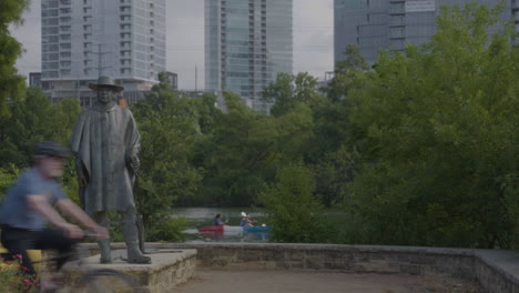 People-passing-in-front-of-Stevie-Ray-Vaughn-statue-in-Austin,-Texas