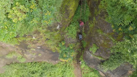 Toma-Aérea-A-Vista-De-Pájaro-De-Un-Joven-Ugandés-Subiendo-Una-Peligrosa-Y-Peligrosa-Escalera-Por-El-Lado-De-Un-Acantilado-En-Un-Valle-Selvático-En-áfrica