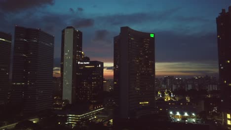 Vista-Aérea-Lateral-Ascendente-De-Un-Dron-Del-Horizonte-De-Singapur-Durante-La-Puesta-De-Sol