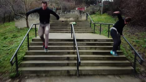 Stabilisierte-Kamerafahrt-Von-Zwei-Parkour-Freiläufern,-Die-Treppen-Hinunterspringen