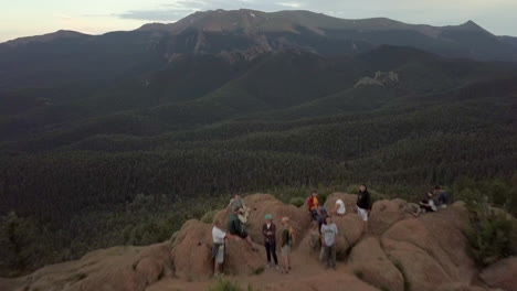 Un-Grupo-De-Excursionistas-Disfrutando-De-Una-Increíble-Vista-De-La-Cima-De-La-Montaña-En-Las-Montañas-Rocosas-De-Colorado,-El-Sobrevuelo-Aéreo-Se-Inclina-Hacia-Arriba-Para-Revelar-Un-Pico-Montañoso-En-La-Distancia