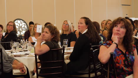 Crowded-venue-full-of-women-listening-to-a-speaker-at-an-event