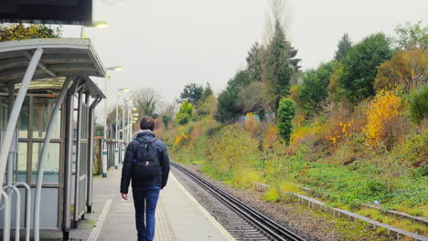 Alejar-A-Un-Hombre-Joven-Que-Camina-Sobre-Una-Plataforma-De-Estación-De-Tren-Vacía