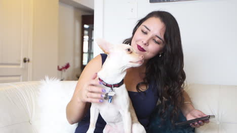 Beautiful-young-woman-petting-and-kissing-her-dog-on-the-couch