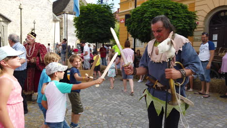 Cámara-Lenta-De-Niños-Campesinos-Peleando-Y-Divirtiéndose-Con-El-Bufón-De-La-Corte,-Recreación-Medieval,-Festival-Preludij-En-Slovenj-Gradec-Eslovenia