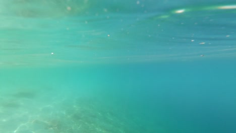 Buceando-En-Las-Hermosas-Aguas-Turquesas-Con-Reflejos-Y-Luz-En-La-Superficie-Y-La-Playa-A-Lo-Lejos