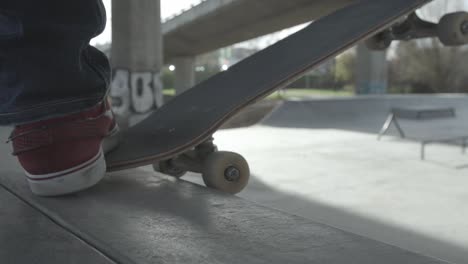 Close-up-shot-of-an-skater-doing-a-drop-in-at-a-huge-bank-ramp-on-a-skatepark