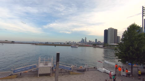 Editorial,-established-shot,-view-of-lake-Michigan-at-navy-pier-Chicago,-panorama,-panoramic-waterfront-view,-buildings,-boat-passing,-people,-birds-and-beautiful-sky-and-clouds