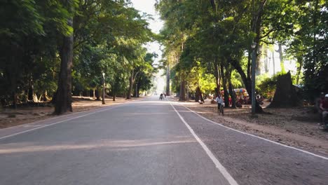 Stabilisierte-Aufnahme-Der-Fahrt-Durch-Angkor-Wat,-Während-Die-Sonne-Durch-Die-Bäume-Scheint