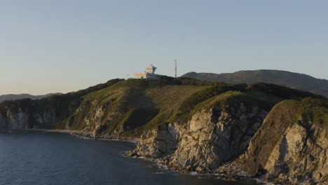 Centro-De-Control-De-Tráfico-Marítimo-En-La-Cima-De-La-Pequeña-Montaña-Con-Acantilados-A-La-Orilla-Del-Mar,-Al-Atardecer,-Rusia,-Lejano-Oriente