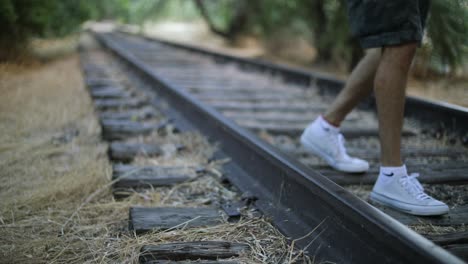 Toma-En-Cámara-Lenta-De-Alguien-Caminando-Sobre-Vías-De-Tren-Abandonadas-Hacia-La-Cámara