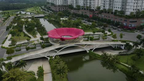 Vista-Aérea-Volando-Hacia-Un-Puente-Peatonal-Contemporáneo-Con-Una-Gran-Flor-De-Sala-Encima