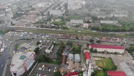 Luftaufnahme-Der-Stadtlandschaft-In-Der-Nähe-Von-Eisenbahnschienen-An-Einem-Nebligen-Tag,-Spur-Nach-Links